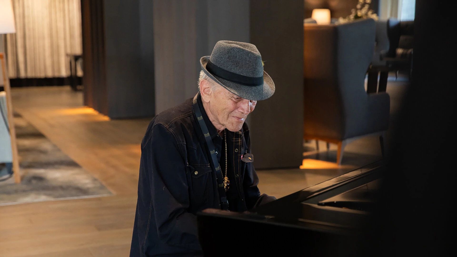 An old man playing on a grand piano