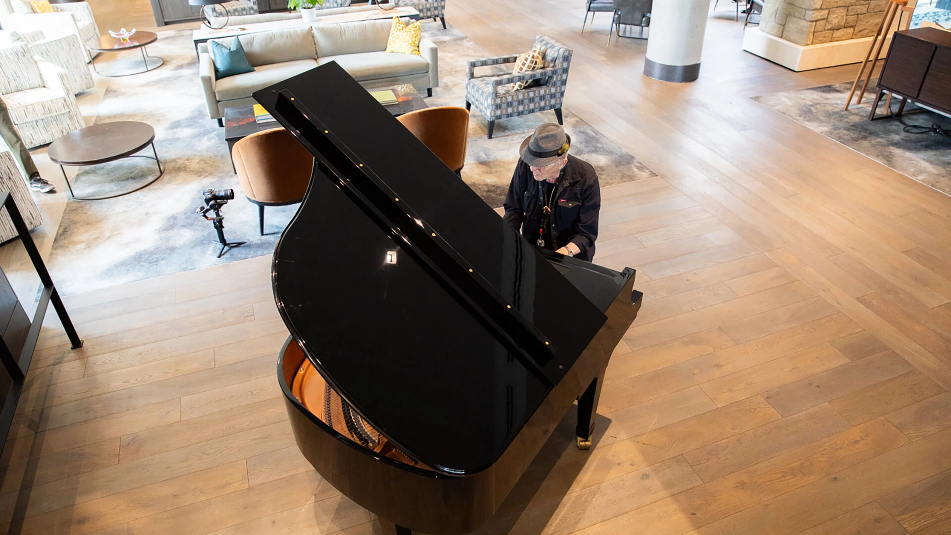 An older man playing a grand piano in the lobby of The Edward