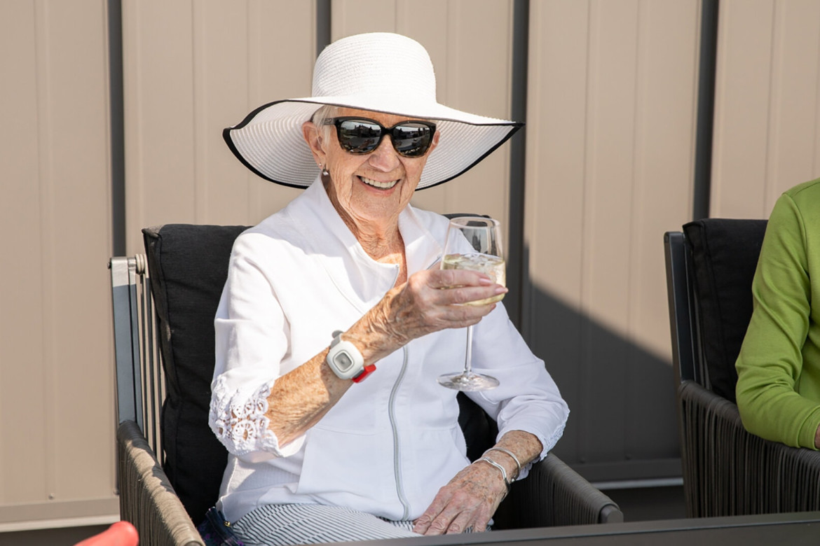 A senior woman drinking a glass of white wine with ice