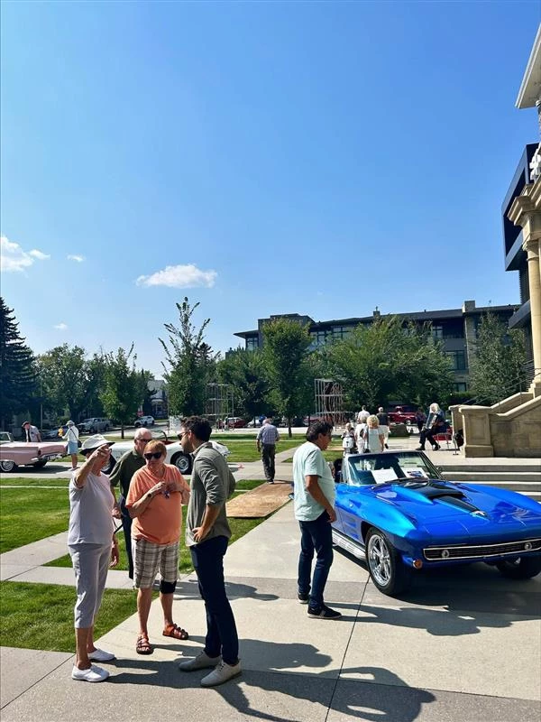 Multiple people standing in front of the building by cars