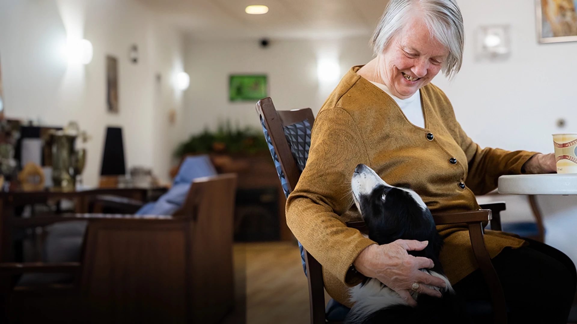 Senior seated and smiling with her dog.
