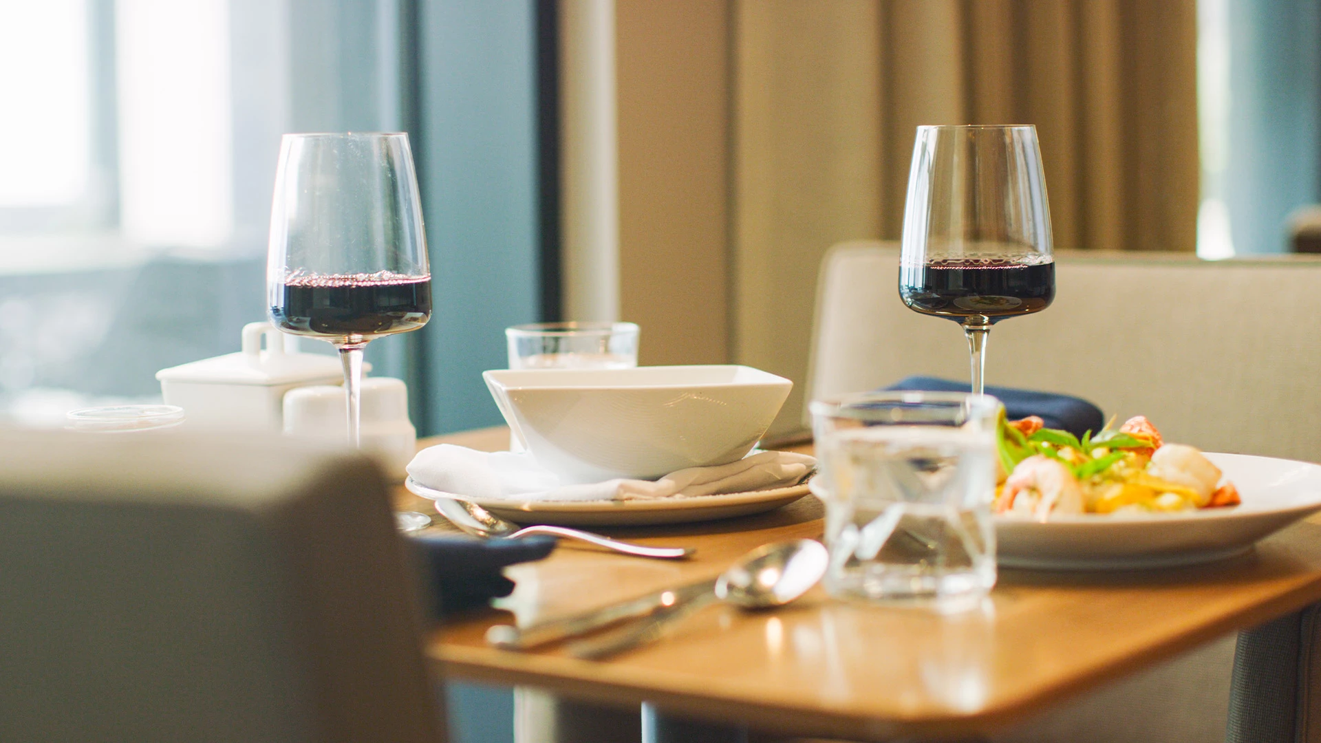 Table set with prawn dish and two glasses of wine