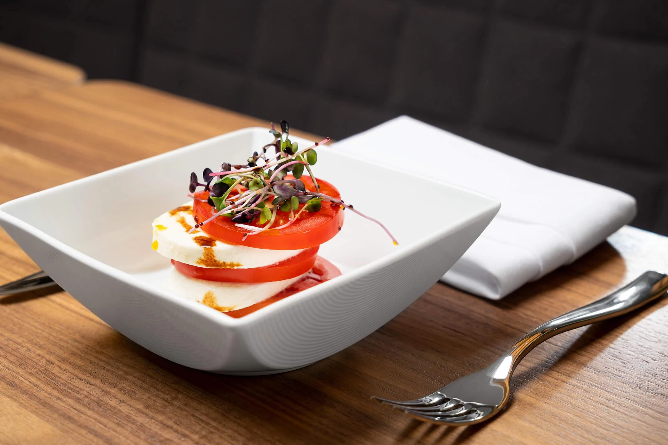 A bowl of mozzarella and tomato salad drizzled with balsamic.